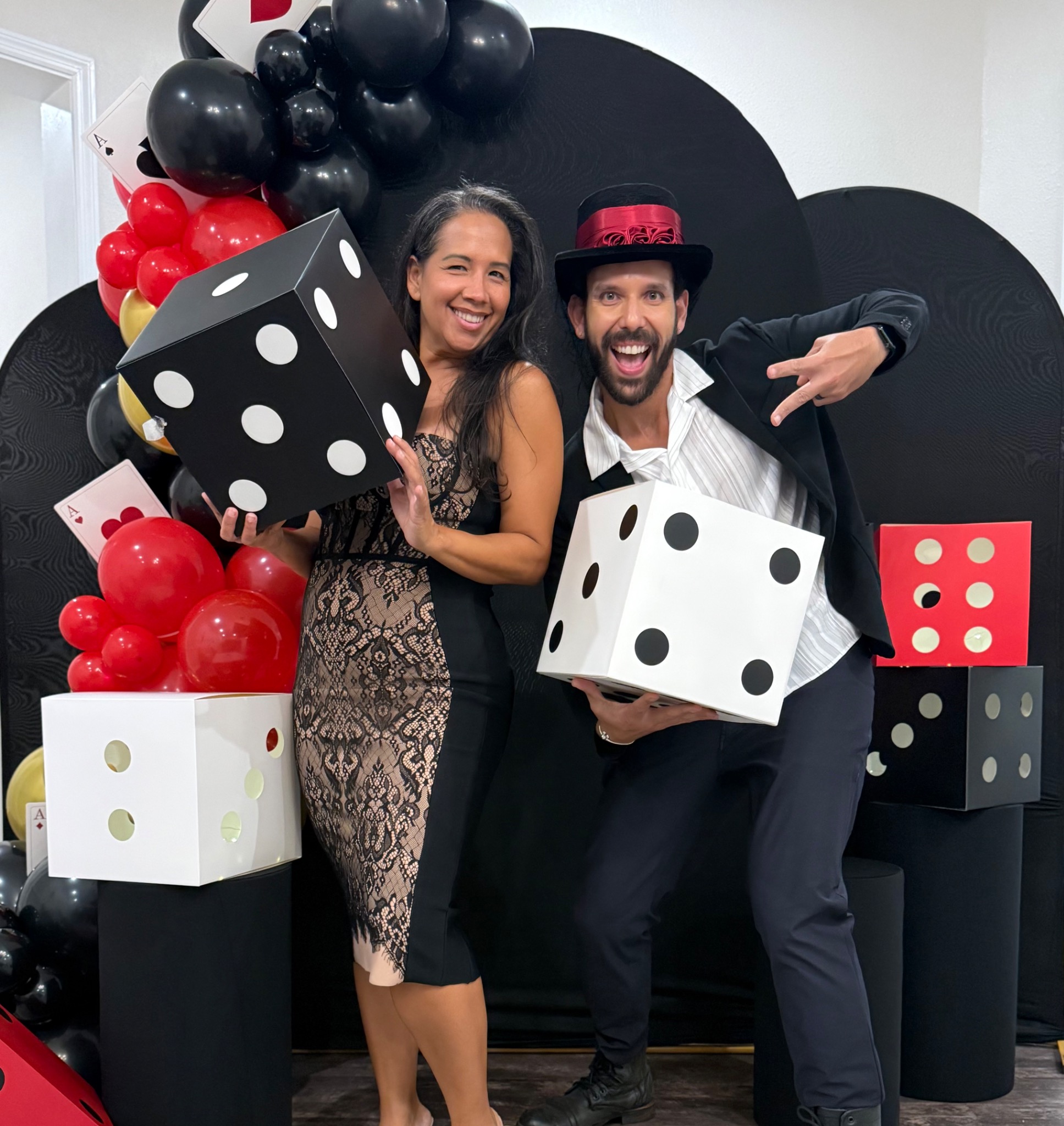 Guests posing with oversized dice in front of a black red and gold casino themed balloon backdrop in Clermont Florida